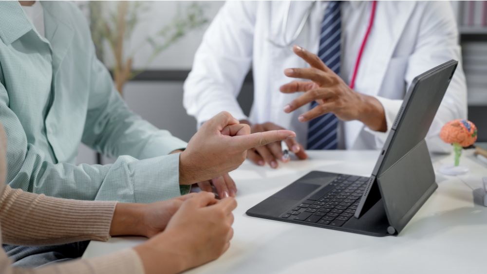Fertility specialist explaining IVF treatment to a couple using charts or tablet